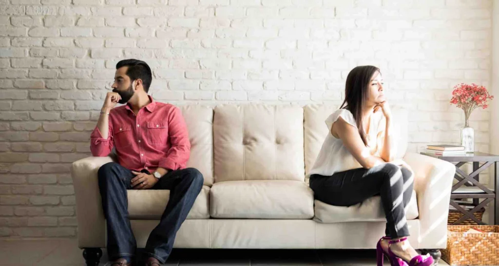 etrennt lebendes Ehepaar sitzt mit Abstand auf einem Sofa