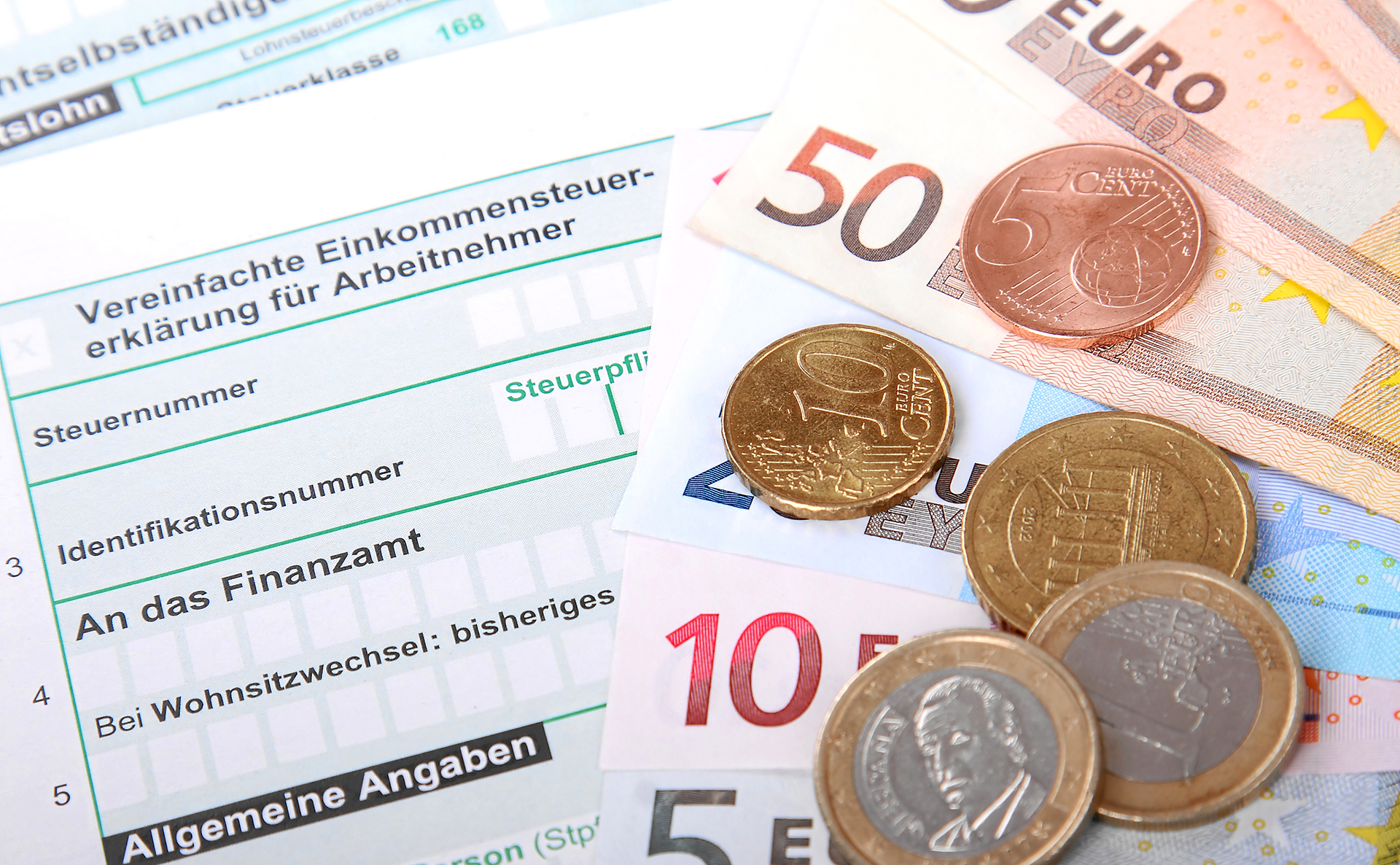 Fotolia XS /Adobe tock Einkommensteuererklärung Formular mit Euro-Geldscheinen und Münzen